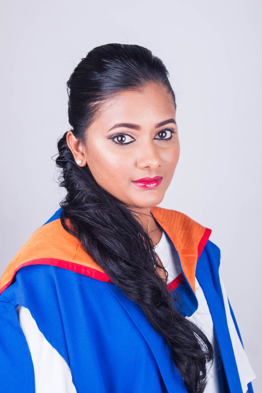 Graduate wearing a blue and orange gown in the portrait studio