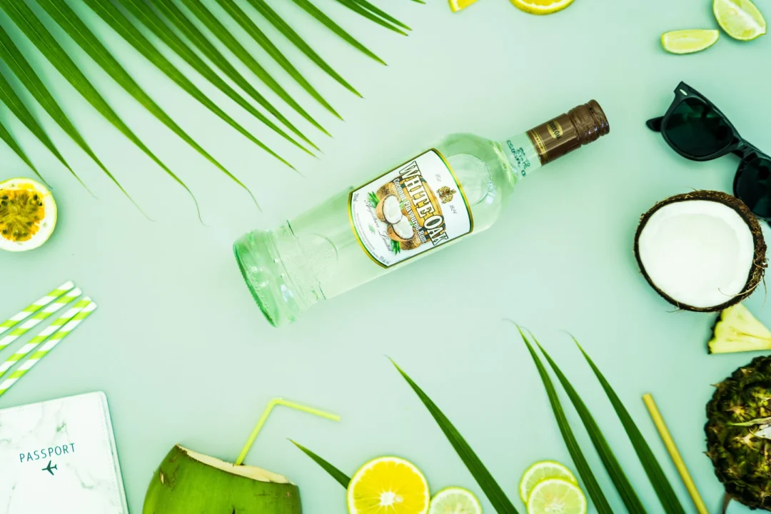 White Oak Coconut rum with coconut, citrus and palm leaves on a mint-green background.