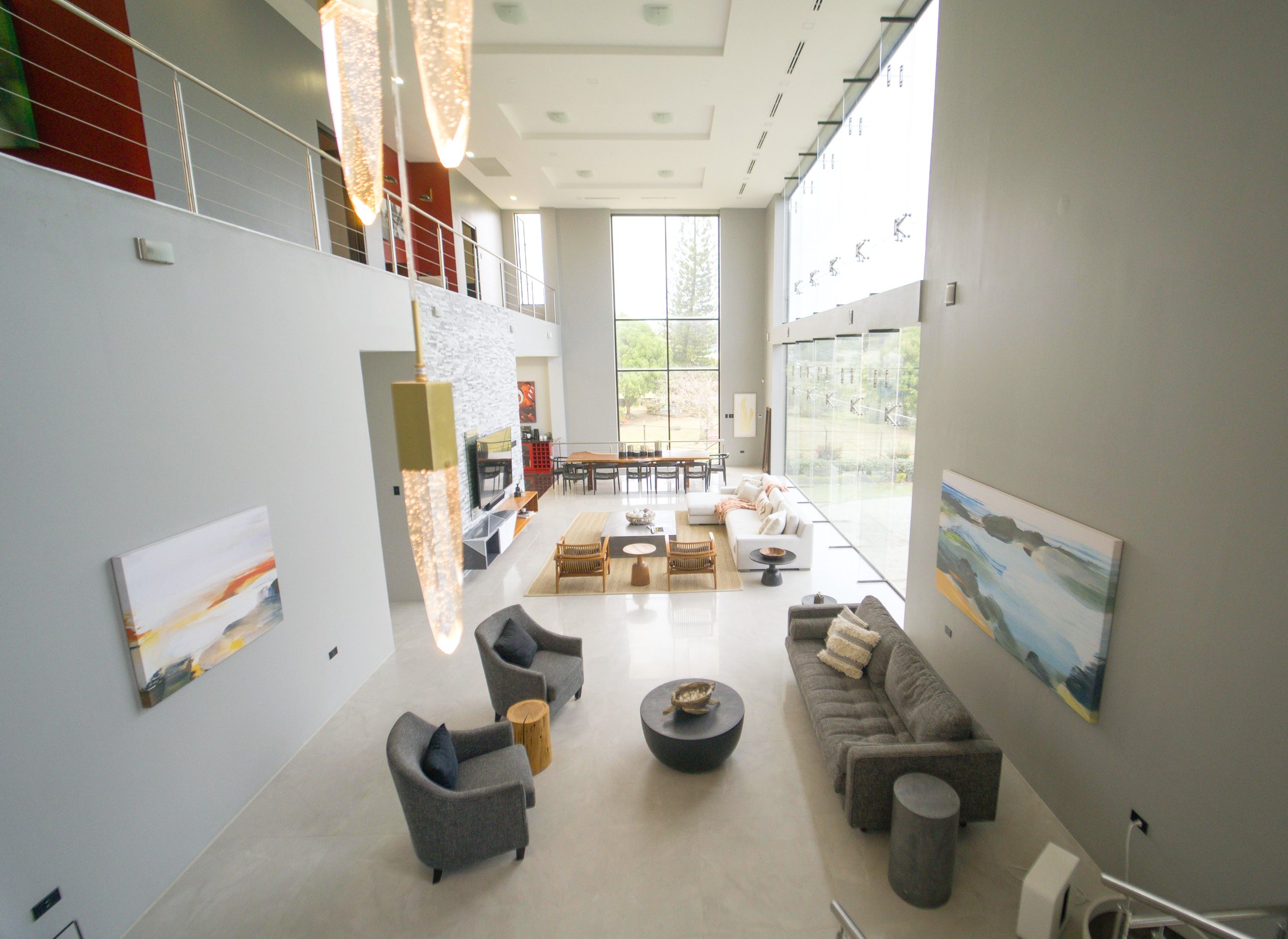 Double-height living room at Villa513 with full-height glass walls and hanging pendant lights.